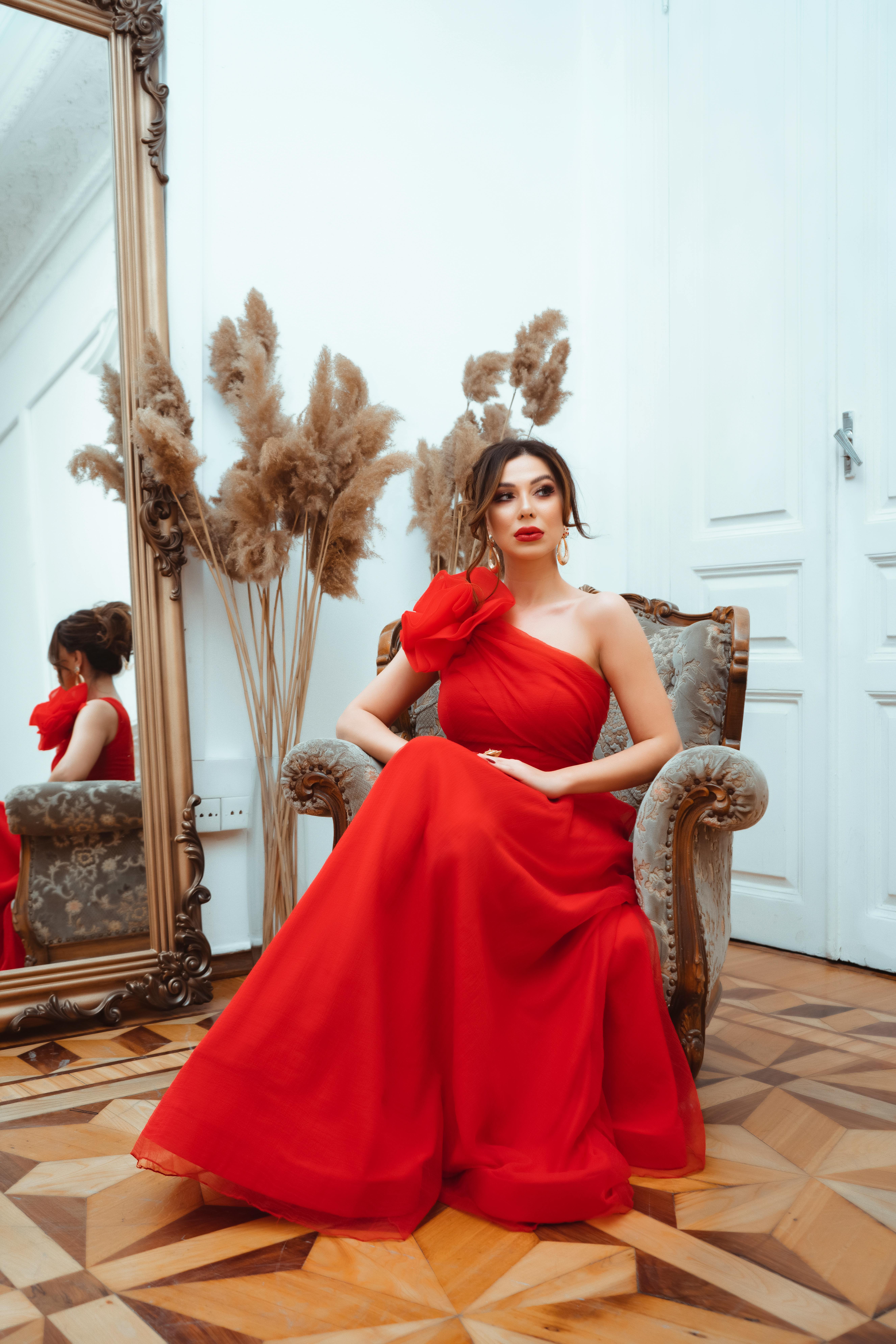 Elegant Woman in Red Gown Seated Indoors  Free Stock Photo