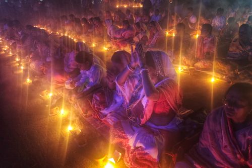 Free Candlelit religious ceremony in Kachua, India, with participants in traditional attire and prayer. Stock Photo