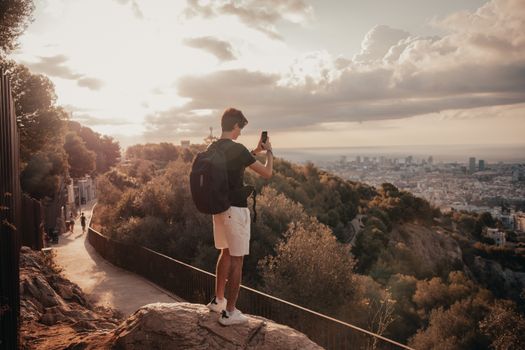A traveler takes photos of Barcelona from a scenic overlook at sunset.
