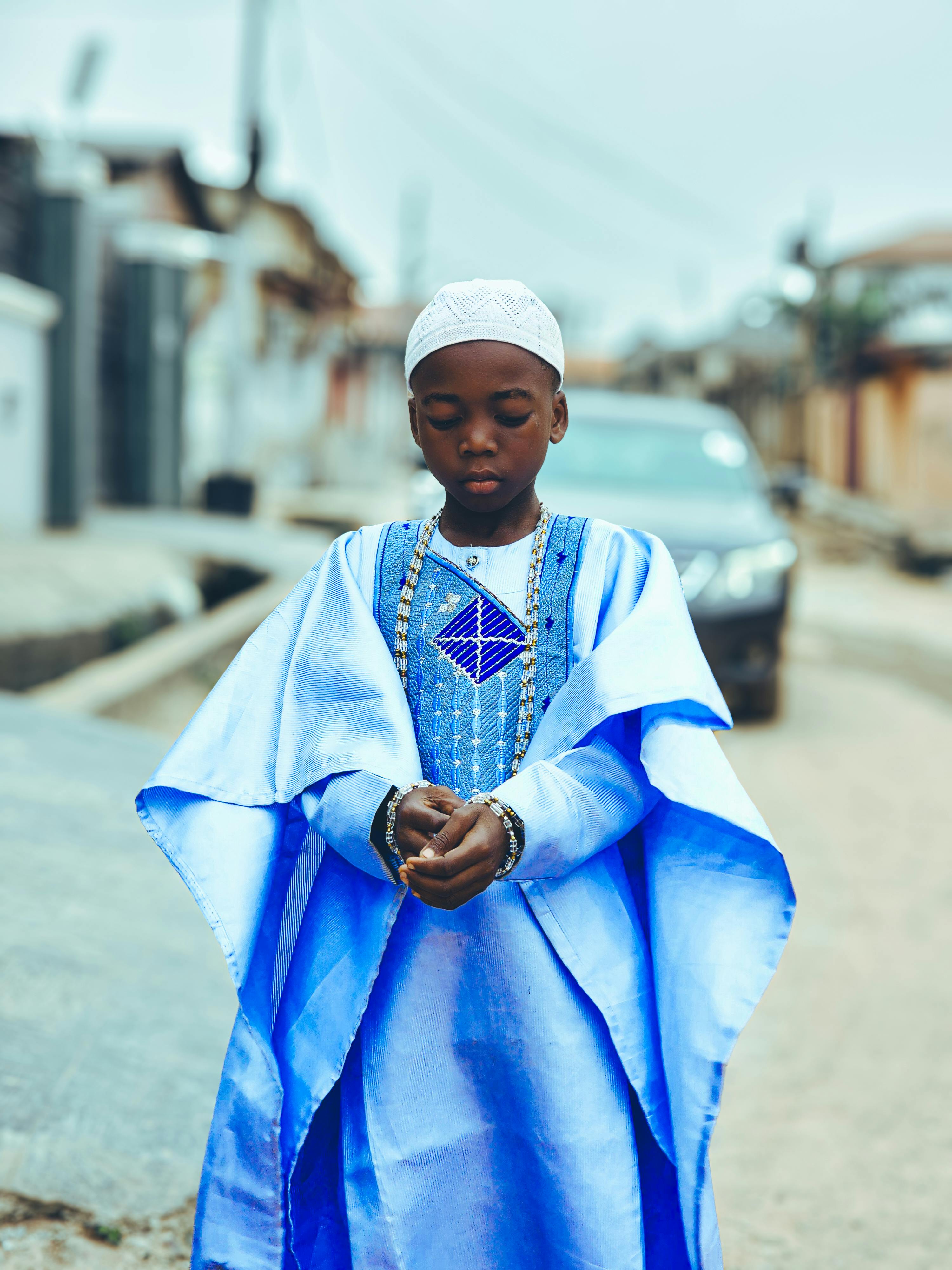 young boy in traditional blue attire on street
