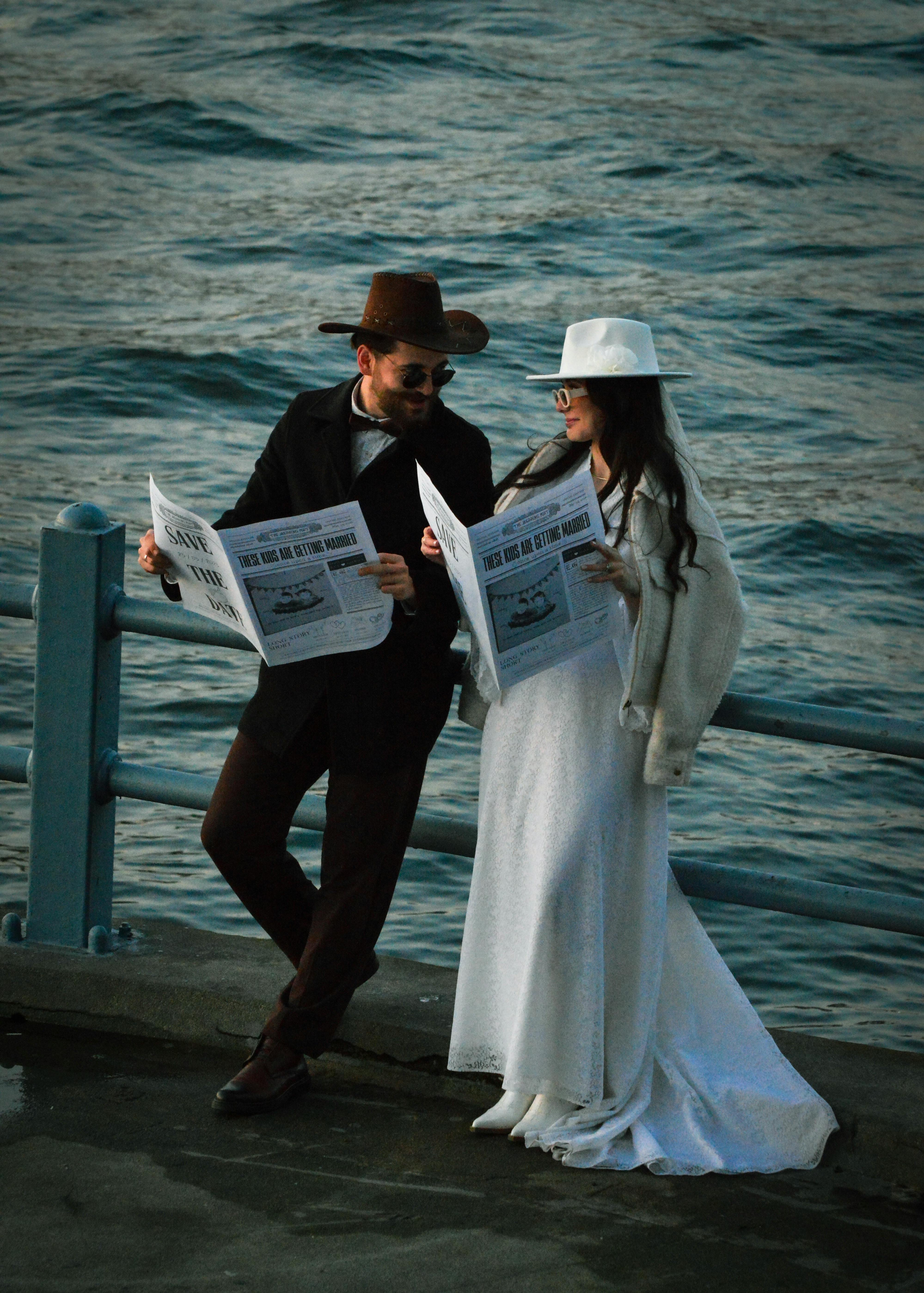 stylish couple reading newspapers by the water