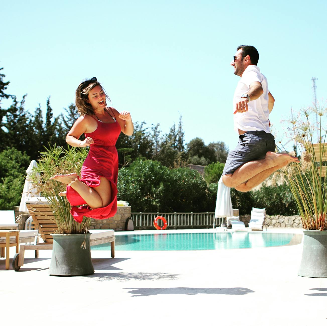 Luxury Relaxation: Unwind At The Best Resort Hotels Around The World 1 a lively couple enjoying a summer day by jumping in front of a luxurious poolside.