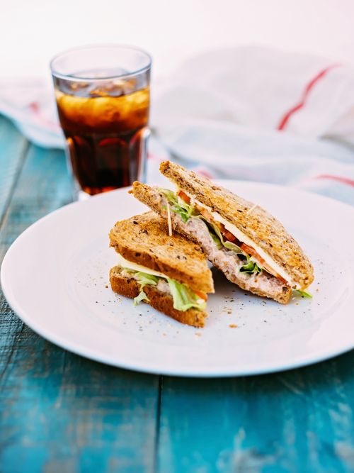Free Tasty tuna sandwich served with fresh vegetables and iced tea on a rustic wooden table, perfect for a healthy lunch. Stock Photo