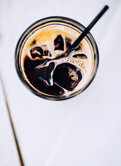 Free Top view of a refreshing iced coffee with a straw on a white background, showcasing rich dark coffee hues. Stock Photo