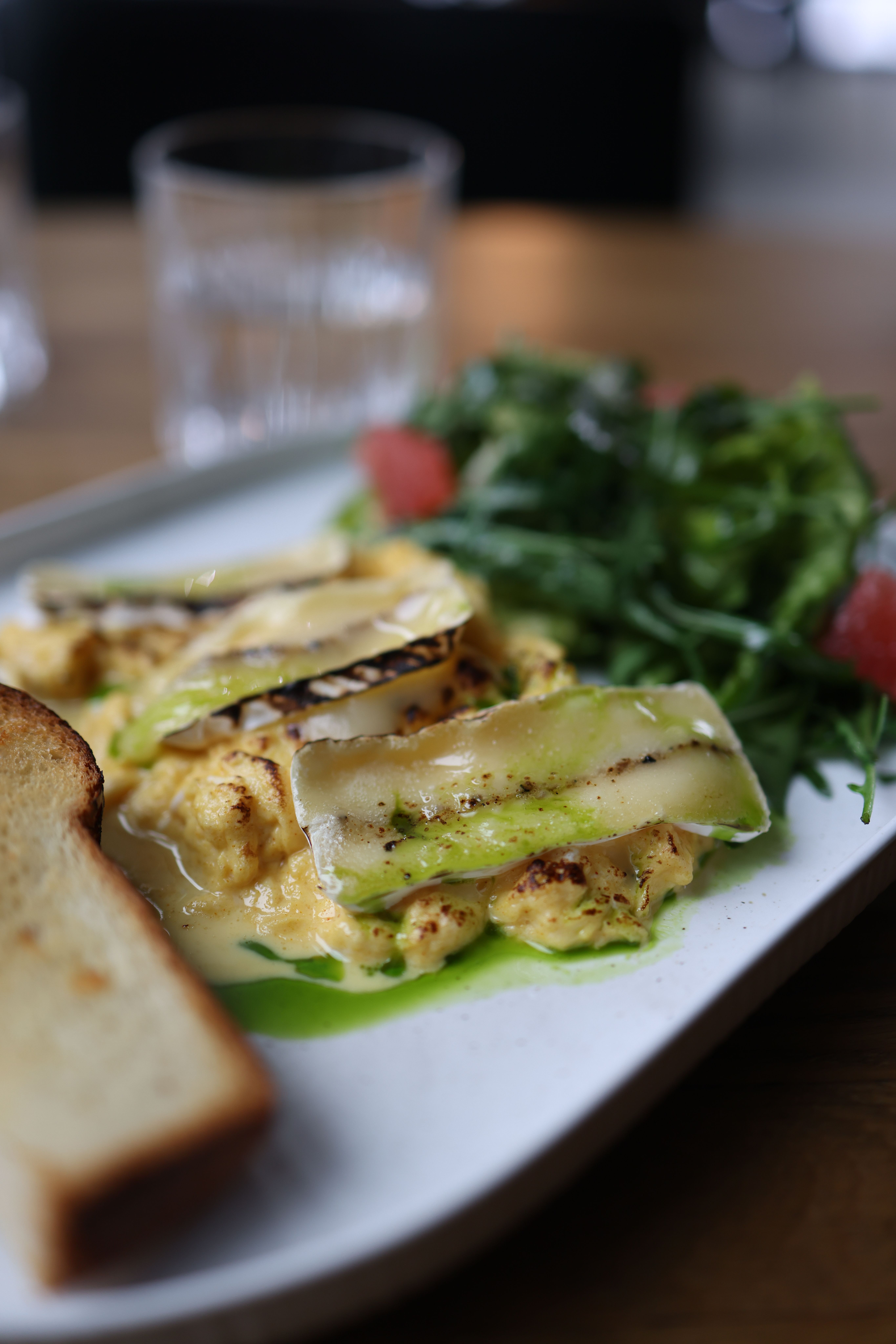 Gourmet scrambled eggs with greens and toast on a elegant plate.