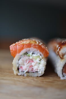 Close-up view of a fresh sushi roll with salmon on a wooden board.