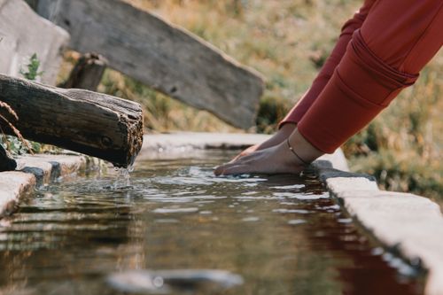Free Hands in a tranquil mountain spring fountain in Trentino-South Tyrol, Italy, showcasing summer refreshment. Stock Photo