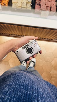 Person holding a vintage camera in a store. Stylish, cozy ambiance.
