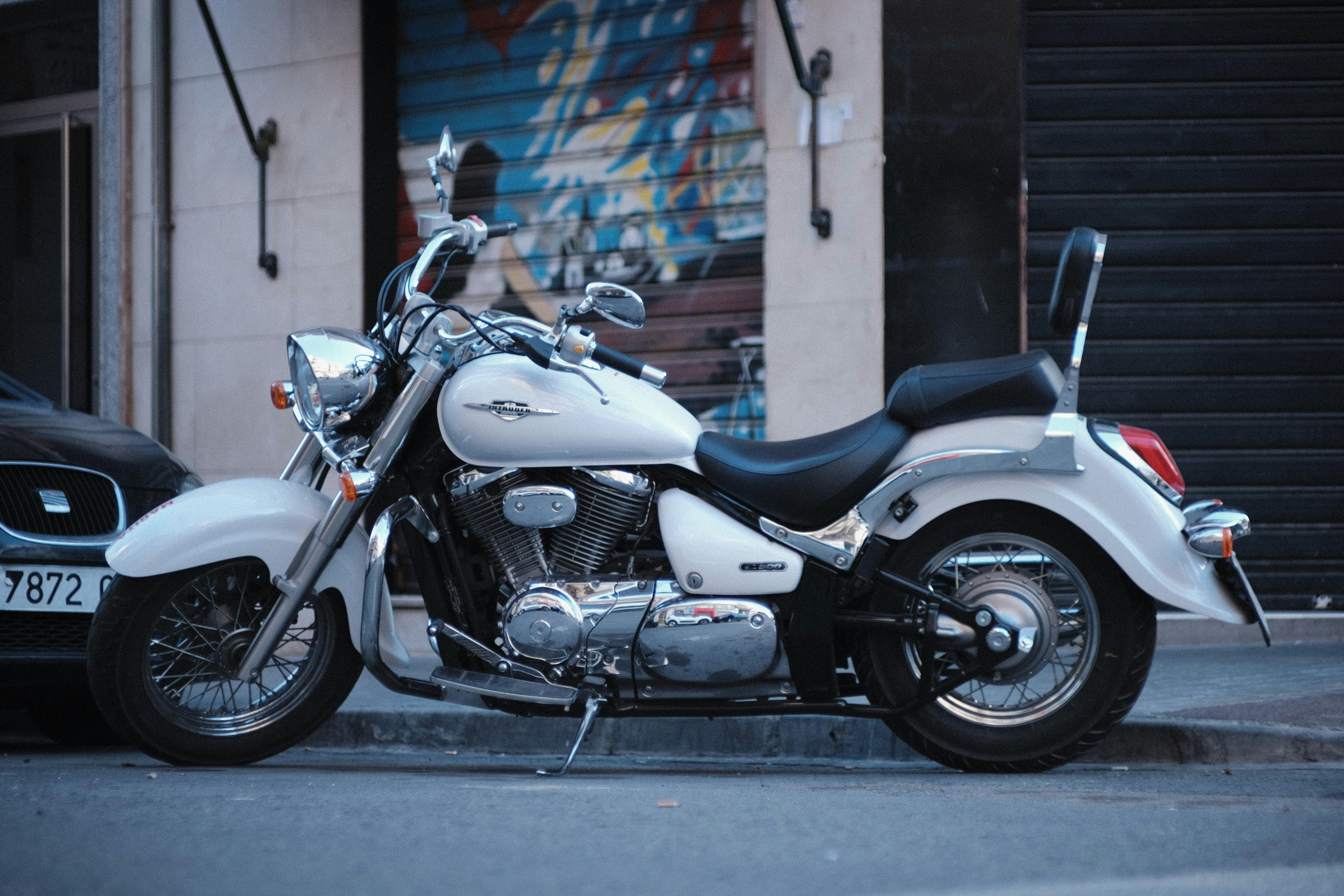 A classic white motorcycle parked on a street in Elche, Spain, showcasing urban lifestyle.