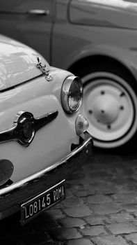 Black and white photo of vintage Italian cars in Rome on cobblestones.