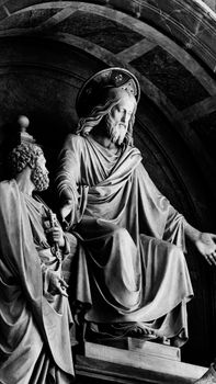 Detailed black and white marble sculptures in a historic archway, showing classic religious figures.