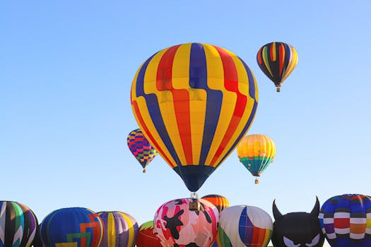 Vibrant hot air balloons soaring in a clear blue sky at a festival.