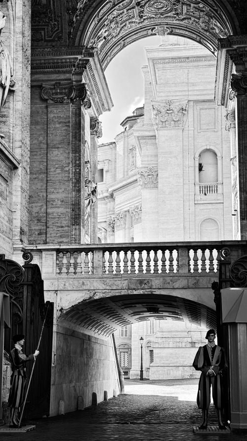 Free Elegant black and white photo of Swiss Guards under a Vatican City archway. Timeless architecture. Stock Photo