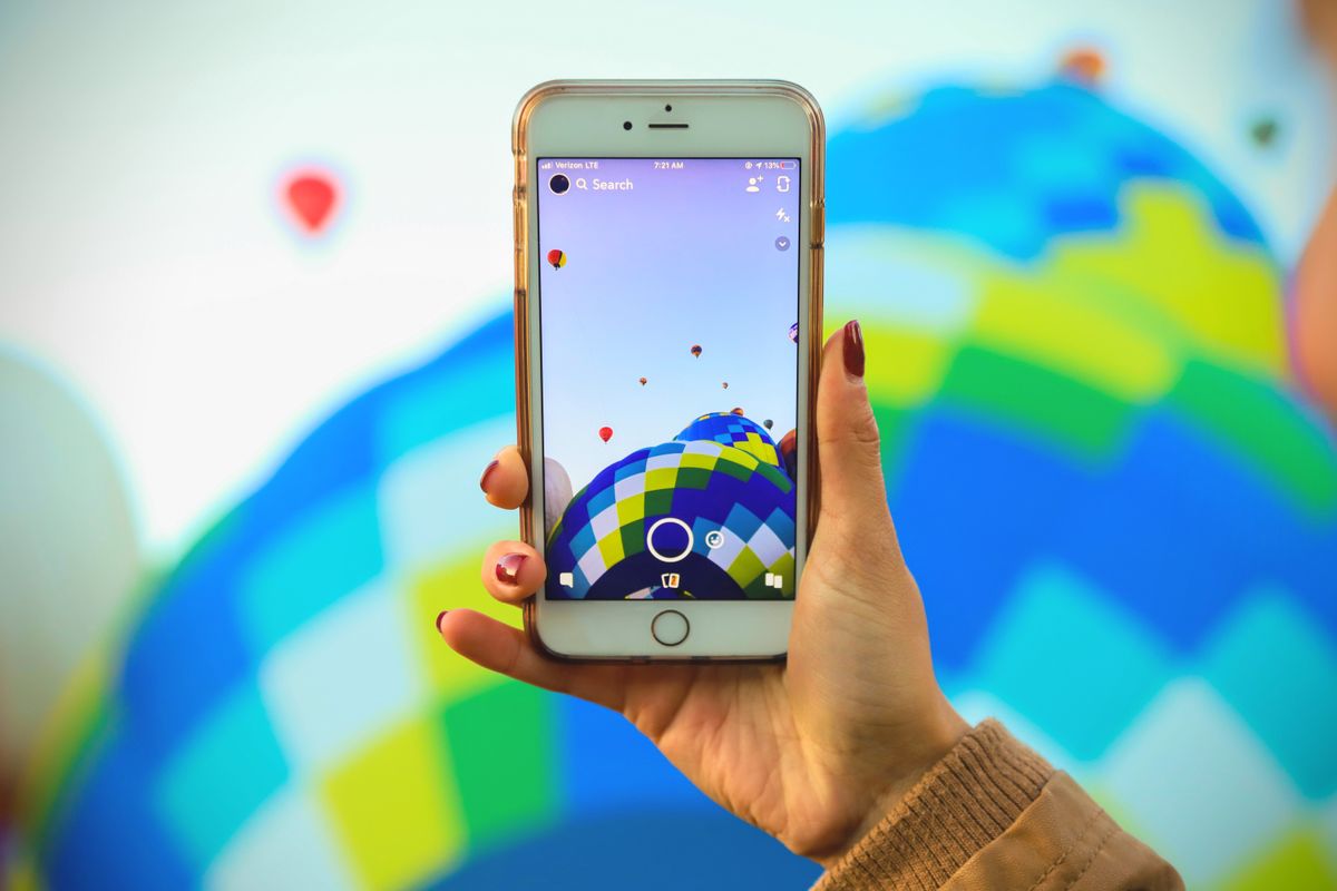 Elinde akıllı telefon tutan kişi, parlak mücevherler arka planda