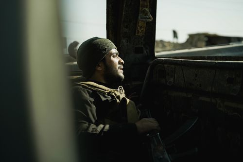 Free A soldier sits inside a dilapidated structure, deep in thought, illuminated by natural light. Stock Photo
