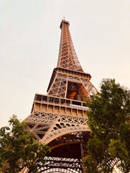 Low-angle view of the Eiffel Tower against a warm sunset sky in Paris, France.
