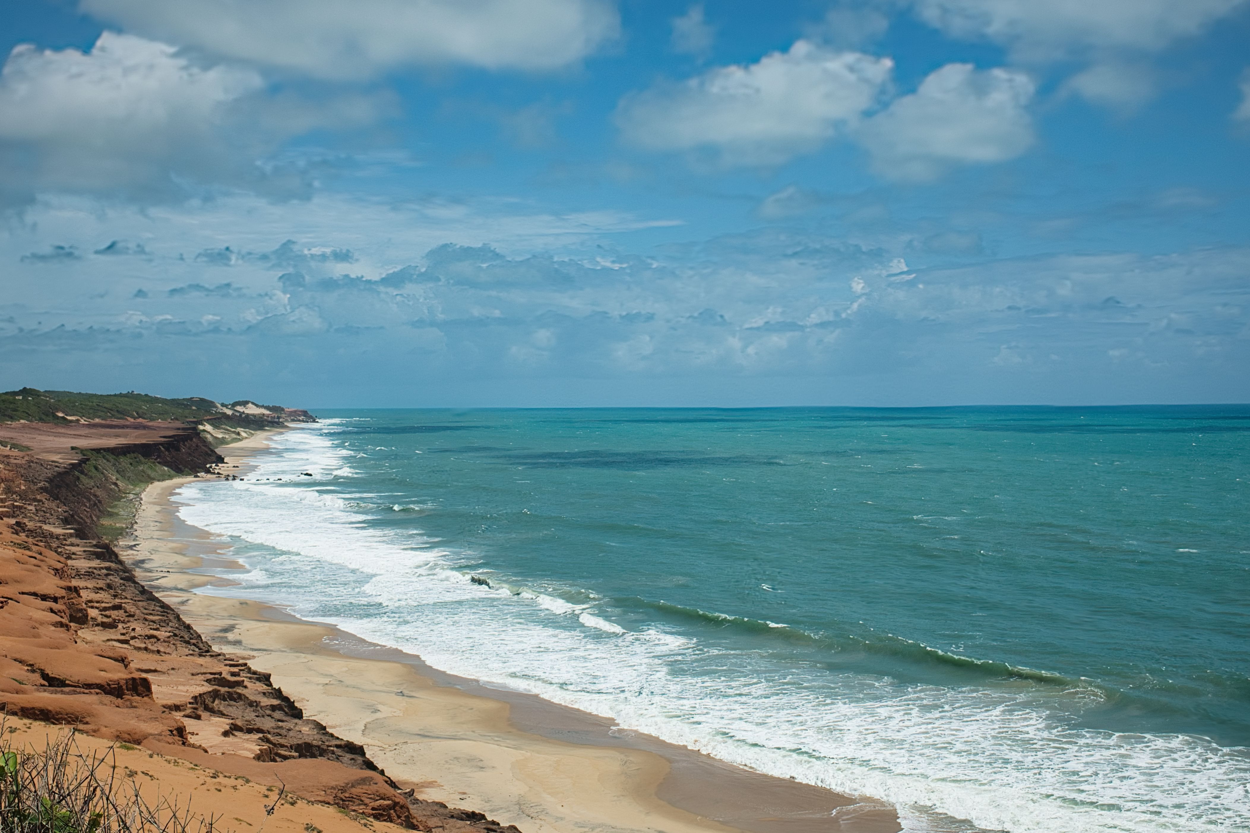 Vibrant ocean scene capturing the cliffs and waves at Pipa Beach in Brazil.