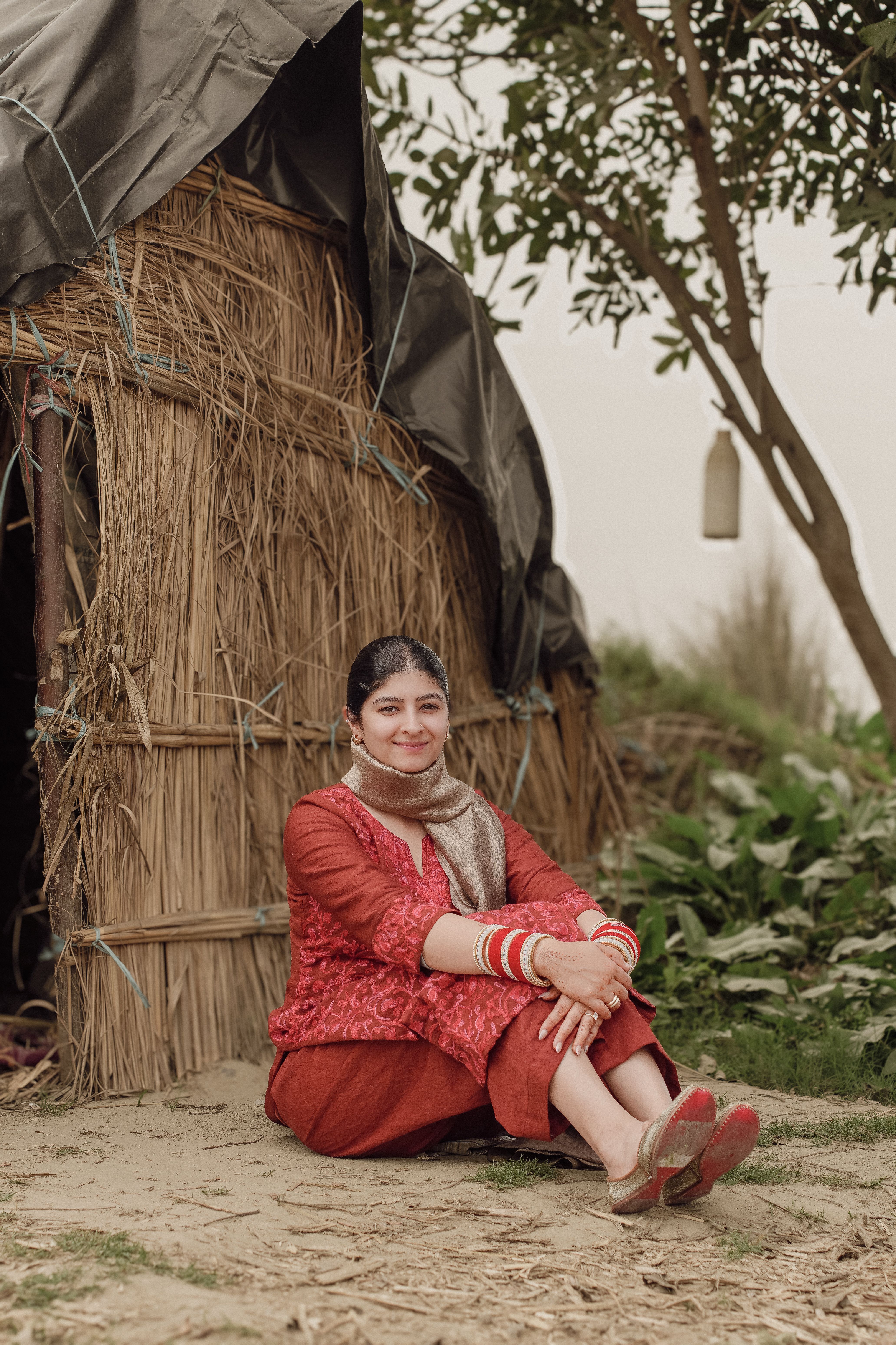 South Asian woman in traditional attire outside a rustic hut in Punjab, India.