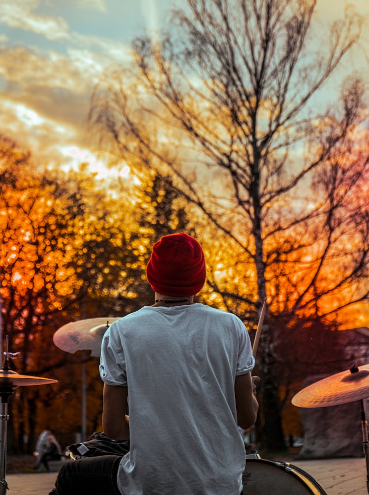 Back View Photo Of Man Playing Drums During Golden Hour