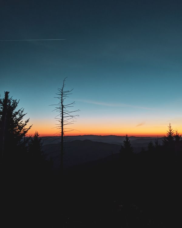 Paisagem serena de montanha com um céu vibrante ao pôr do sol, exibindo a beleza e a tranquilidade da natureza.