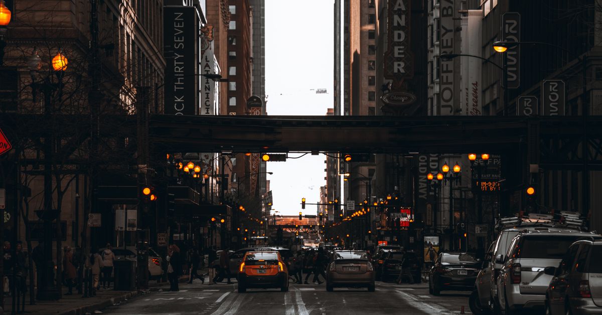 Vibrant street scene in downtown Chicago capturing cars, people, and illuminated city lights at dusk.