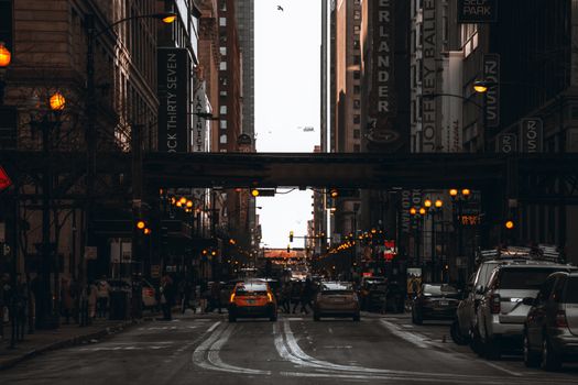 Vibrant street scene in downtown Chicago capturing cars, people, and illuminated city lights at dusk.