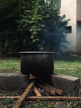 A cast iron pot over a campfire in a rustic outdoor setting.