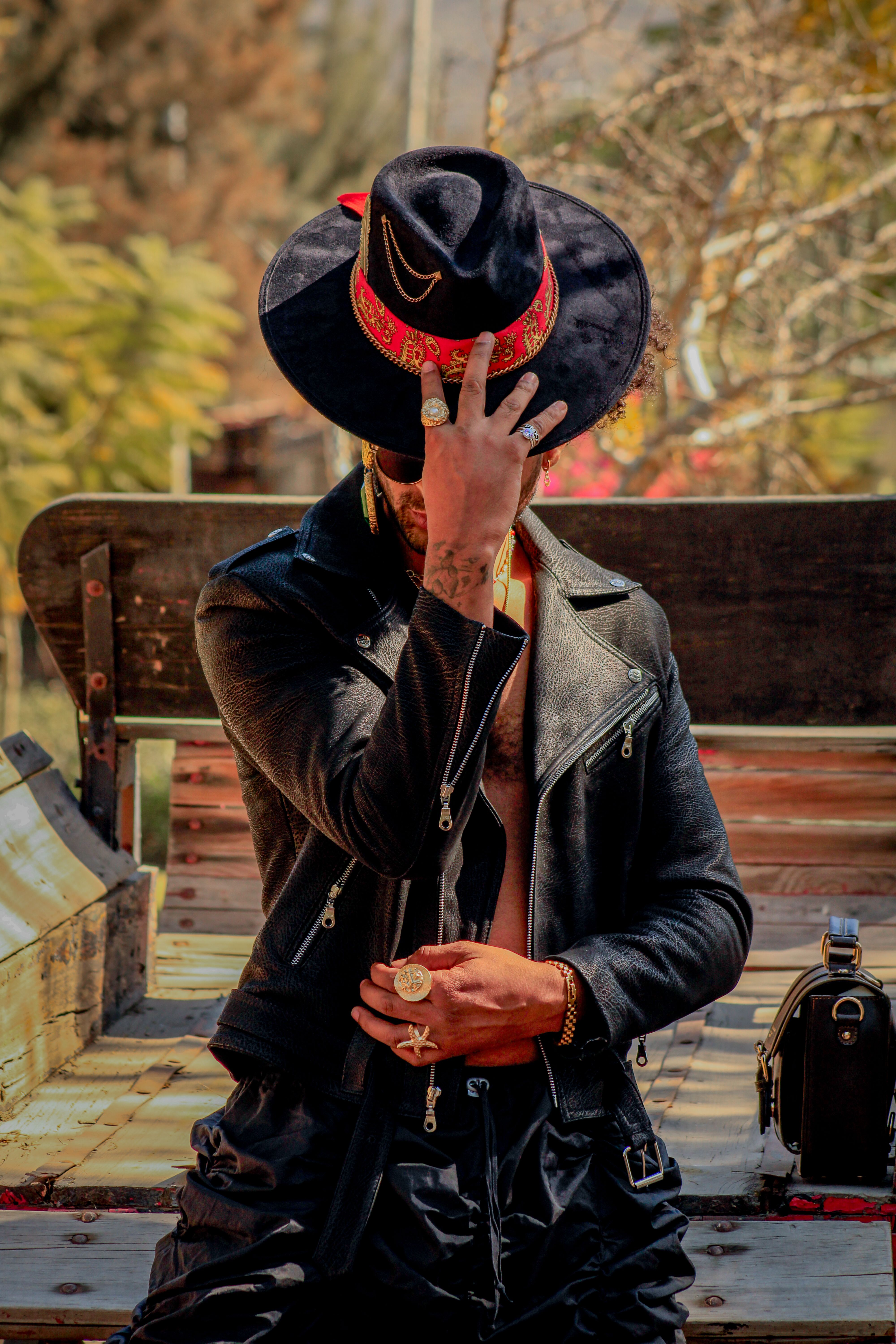 A fashionable man wearing a leather jacket and hat poses outdoors in Ibarrilla, Guanajuato.