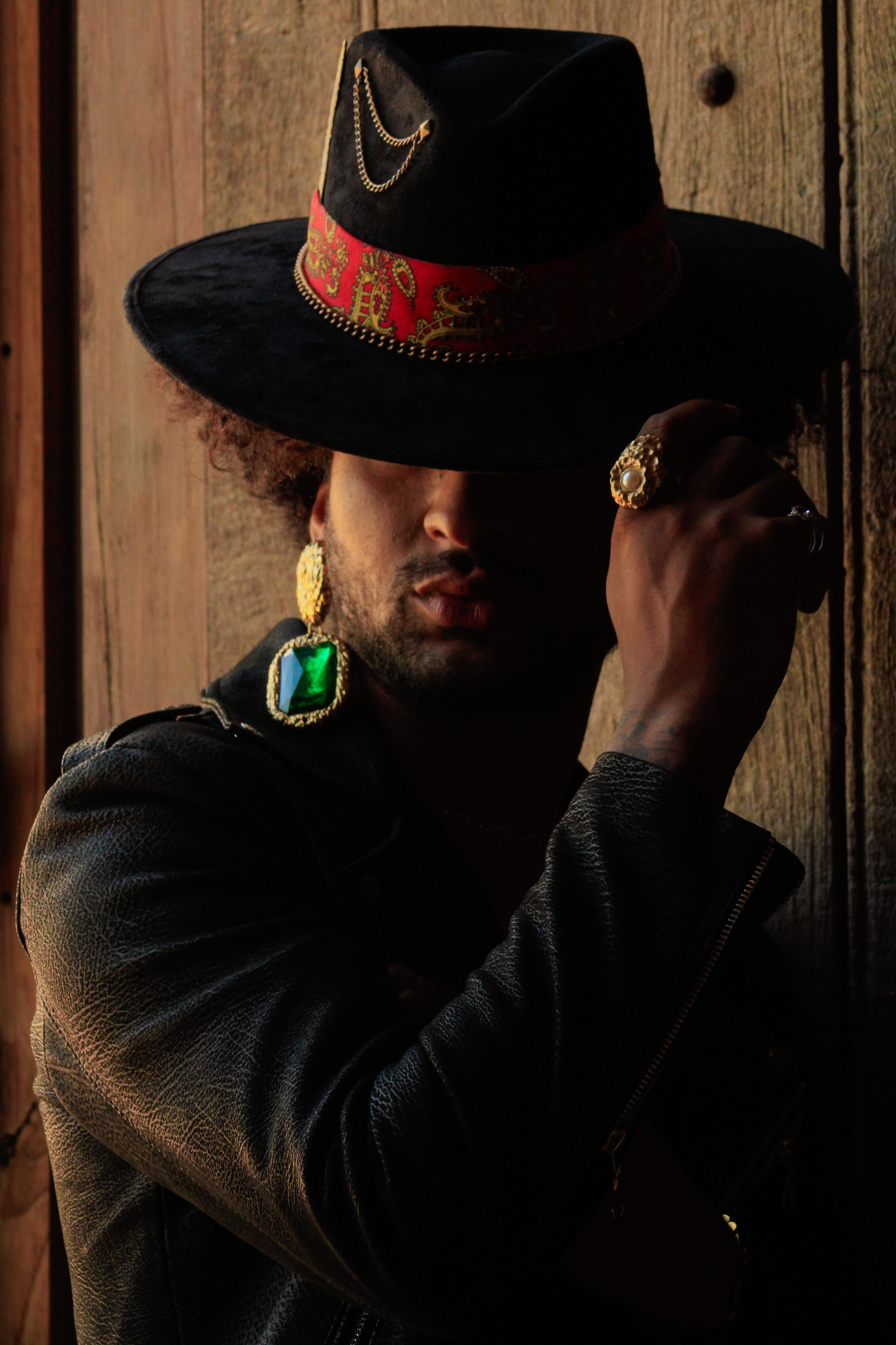 Fashionable man wearing statement jewelry and a hat in rustic Ibarrilla, México setting.