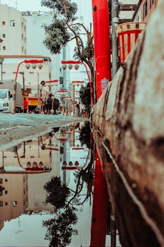 雨水坑中倒映着迷人的城市街道，其间点缀着充满活力的红色装饰与城市建筑