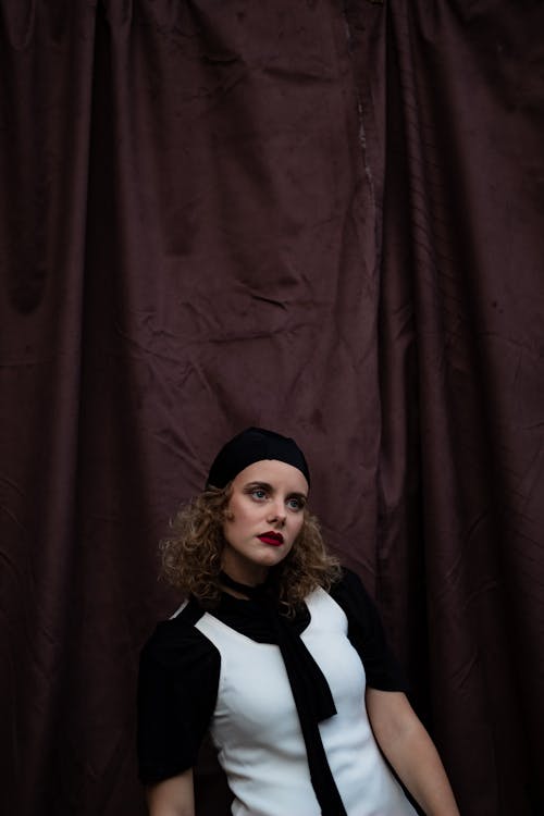 Confident dreamy woman in hat and dress in studio