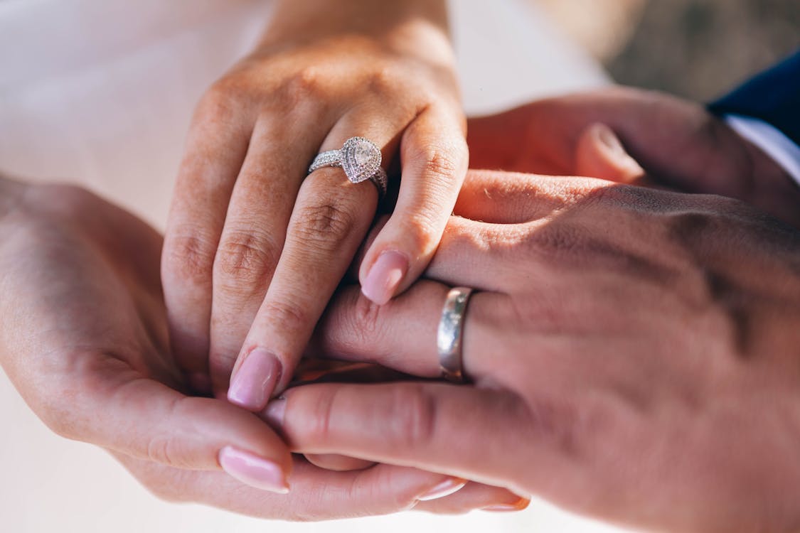 An image of a couple holding hands wearing wedding bands