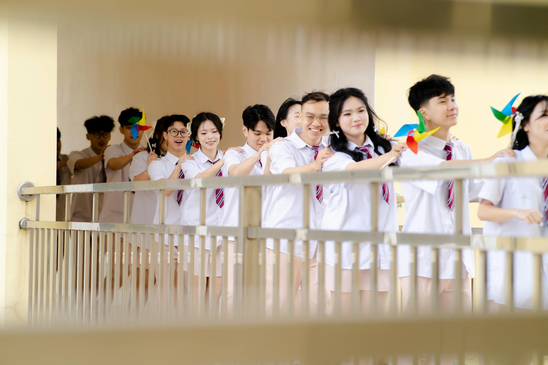 A joyful group of students in uniforms holding colorful pinwheels, standing in line.