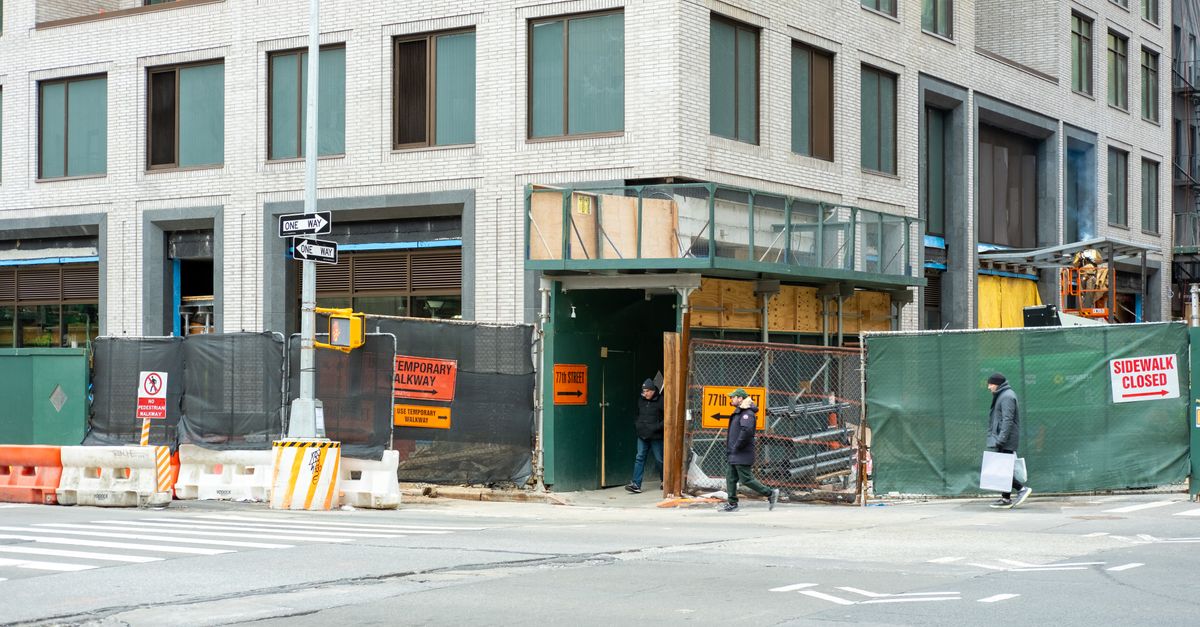City streetscape featuring a building under construction with closed sidewalk signage.