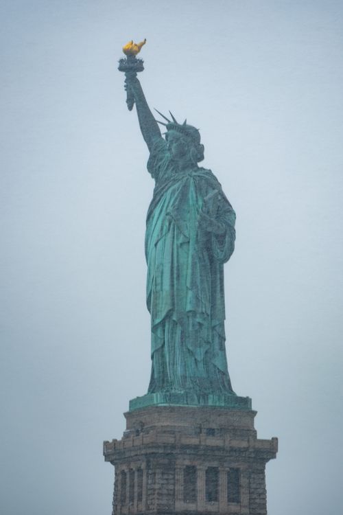 Free Iconic Statue of Liberty under a cloudy winter sky, symbolizing freedom in New York City. Stock Photo