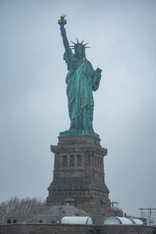 Free The iconic Statue of Liberty rises through the fog on a cold, snowy winter day in New York City. Stock Photo