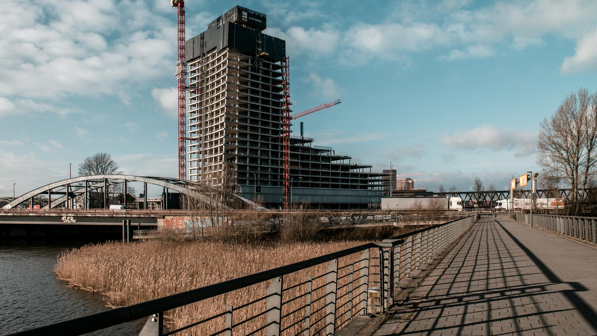 A high-rise building under construction in Hamburg, showcasing modern architecture with cranes and surrounding infrastructure.