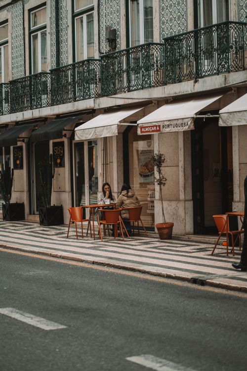 Free Outdoor café scene in Lisbon showcasing local architecture and relaxed urban lifestyle. Stock Photo