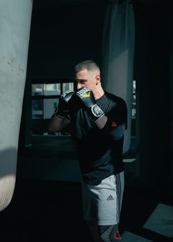 A male boxer in a gym focusing on punching techniques with a punching bag.