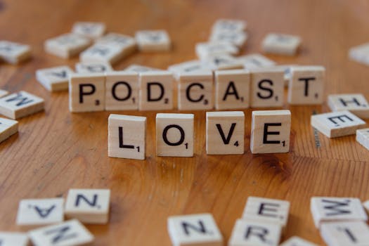 Scrabble tiles spelling 'PODCAST' and 'LOVE' on a wooden surface.