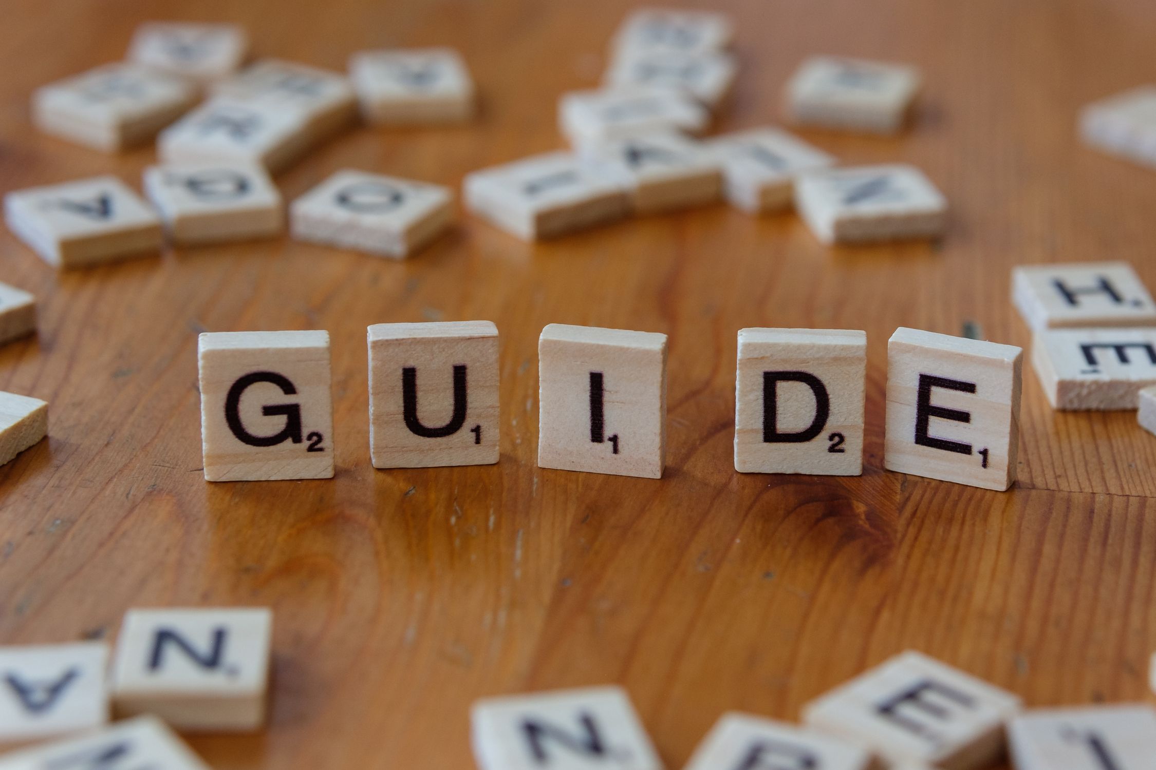 Know Scrabble Block Scrabble Tiles Spelling 'Guide' on Wooden Surface · Free Stock Photo