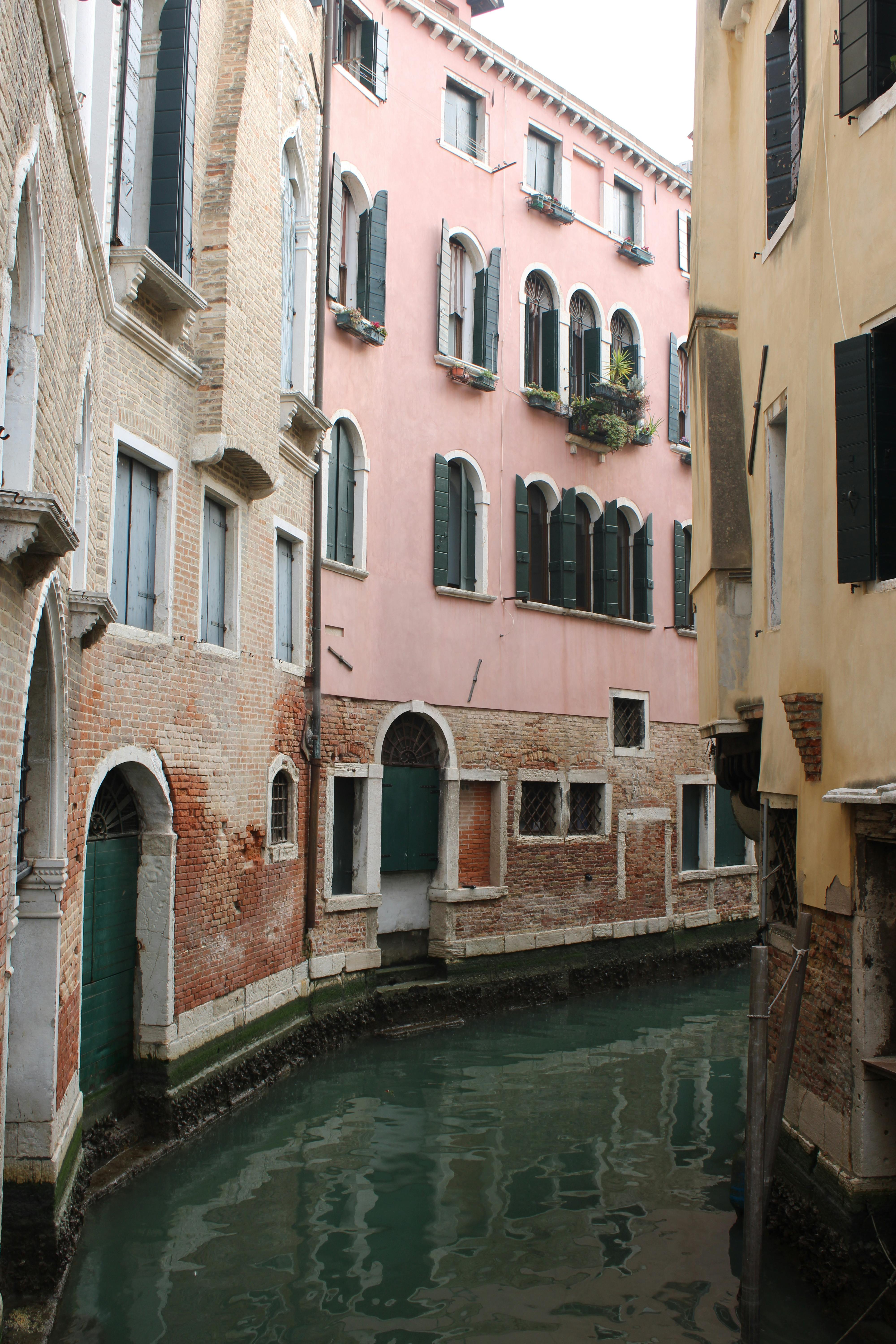 Scenic view of a quiet canal in Venice lined with historic, colorful buildings.