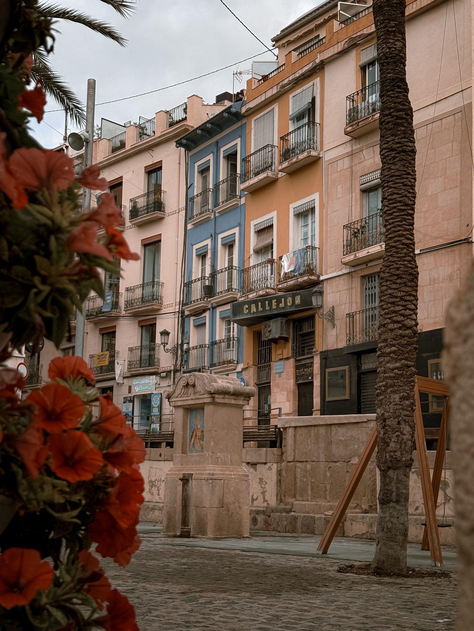 Cazare în Alicante: piațetă cu case colorate și palmieri în orașul vechi