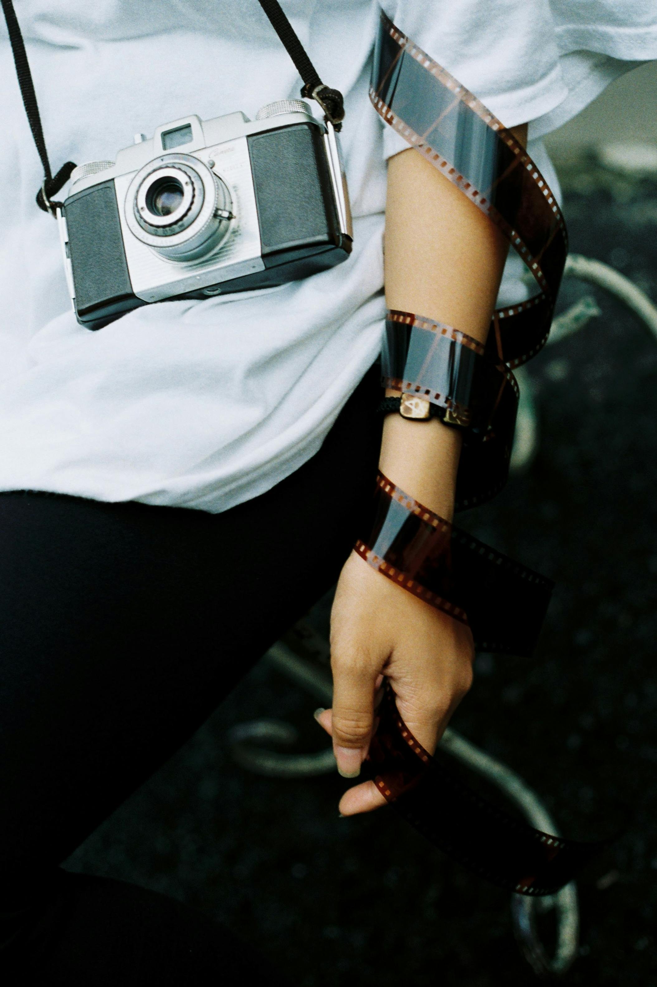 Close-up of a person holding a vintage film camera and film roll, suggesting classic photography.