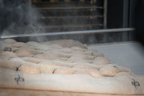 Free Artisan bread cooling on a rack in a Berlin bakery, dusted with flour. Stock Photo