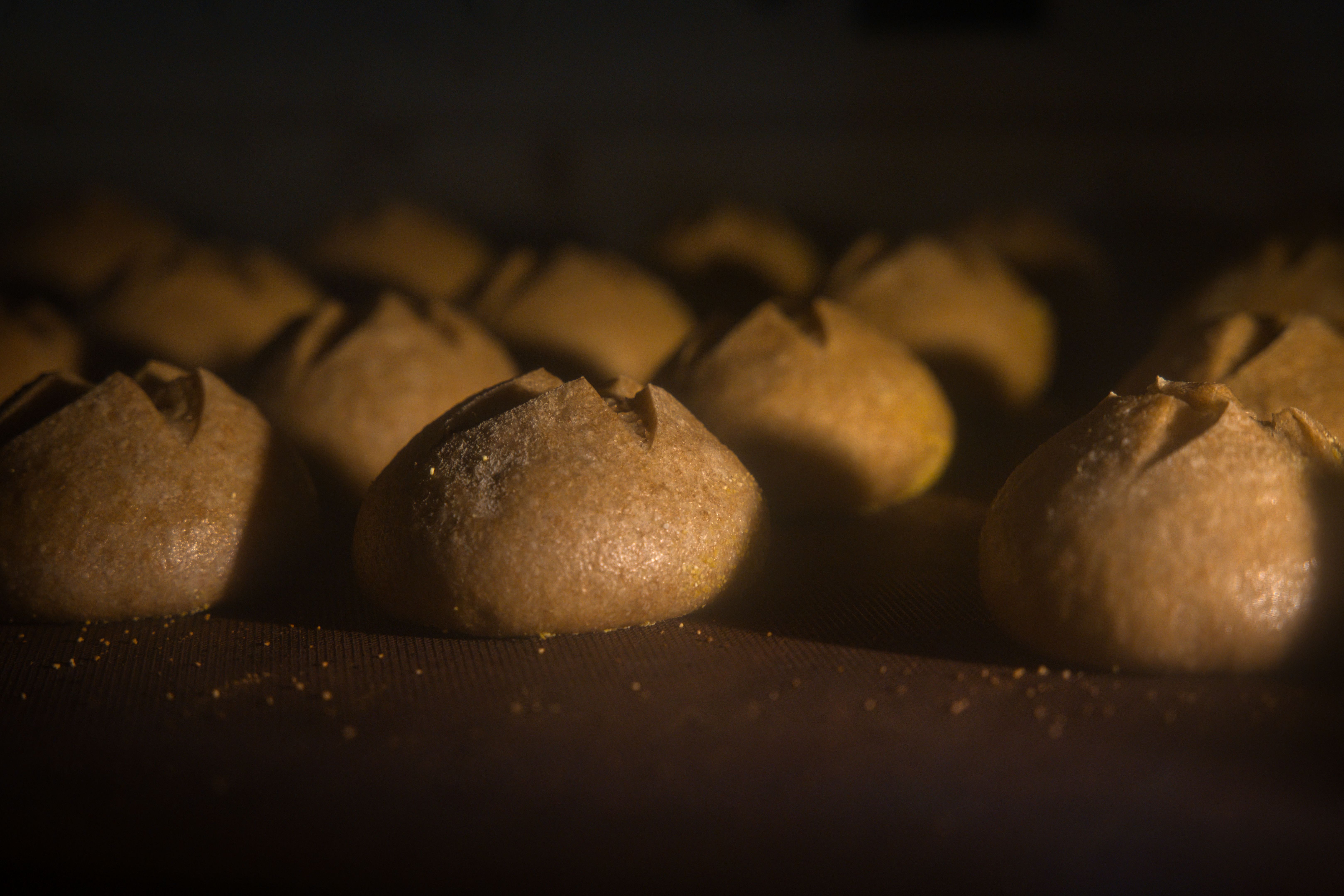 Warmly lit image of artisanal breads baking in an oven, showcasing rustic textures and craft.