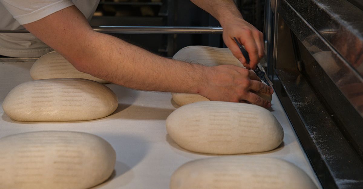 Un boulanger de Berlin façonne des pains artisanaux sur une plaque de cuisson dans une boulangerie artisanale.