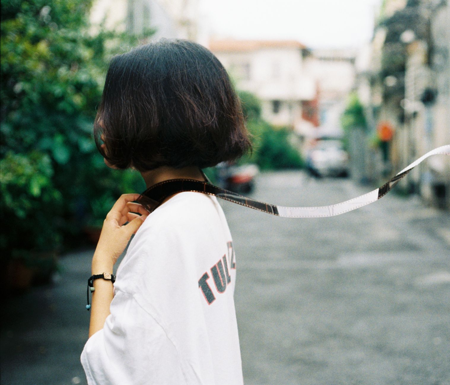Young woman holding camera strap on a street in Ho Chi Minh City.