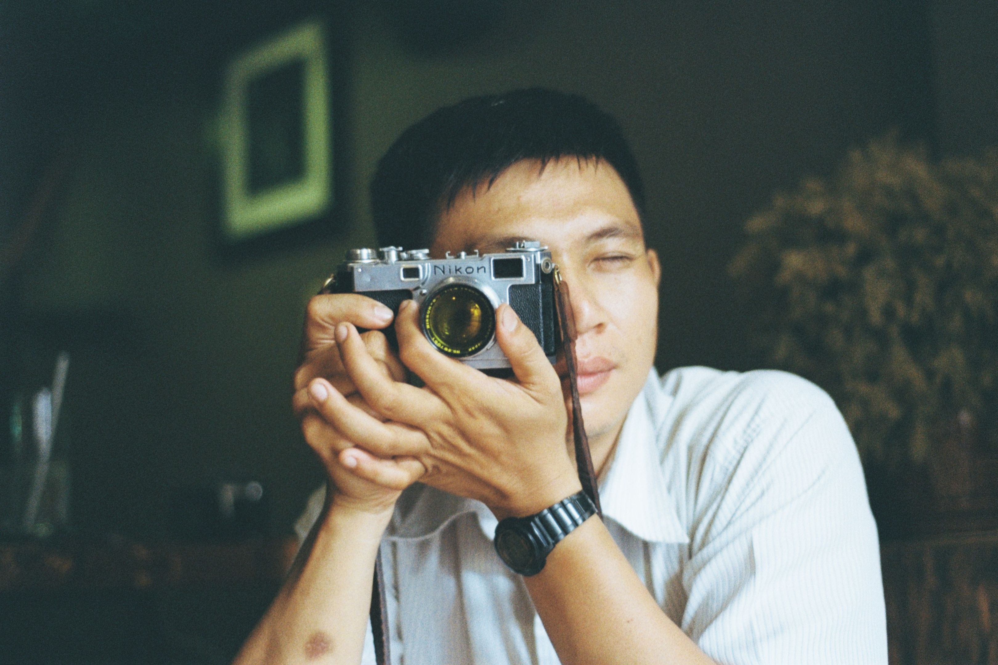 Man holding vintage Nikon camera in Ho Chi Minh City, Vietnam.