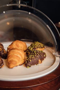 A delectable display of croissants with chocolate and pistachio in a bakery case.
